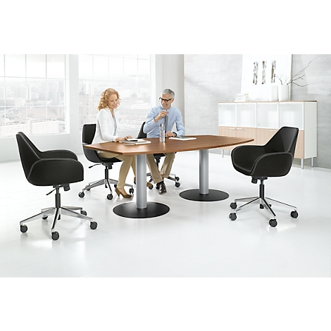 Two people sit at a table, two chairs are free. The room is bright and modern.