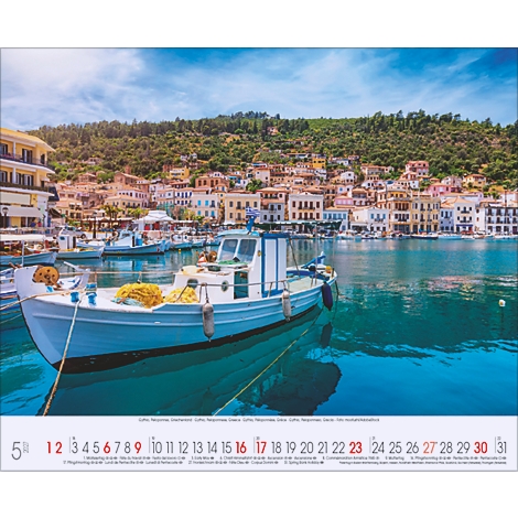 Un bateau devant une ville côtière avec des maisons colorées et des collines verdoyantes. En premier plan la date.