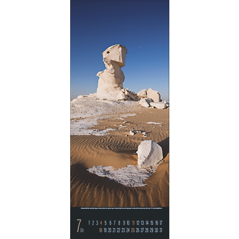 Un panorama désertique avec une formation rocheuse blanche sur fond de ciel bleu profond. La surface ondulée du sable avec des ombres sombres.