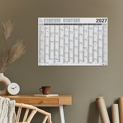 Calendrier mural pour 2027 sur un mur. Tasse, horloge et vase sur un bureau.