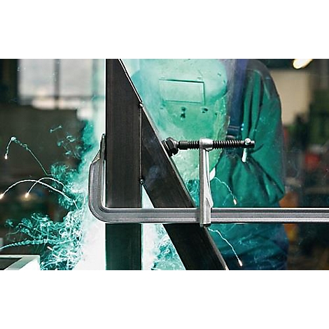 Lasser in beschermend masker die metalen onderdelen last, vonken.
