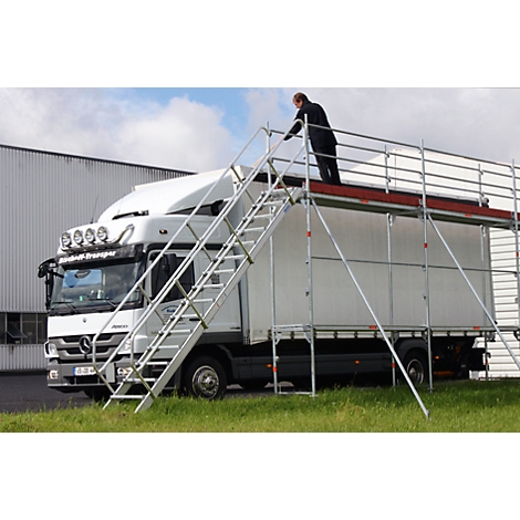 Man on scaffolding next to truck. Scaffolding with stairs to the truck roof. Inscription on truck: "Transport"