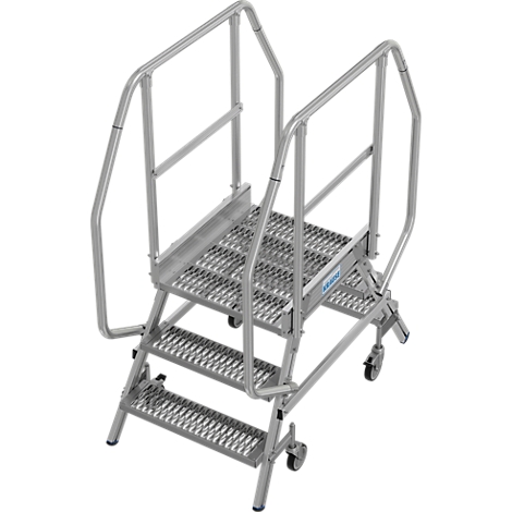 Een zilveren mobiele trap met drie treden, een platform en leuningen. Hij staat op wielen.