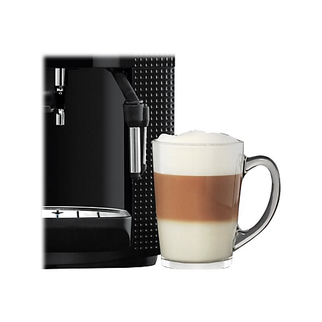 Kaffeevollautomat neben einem Glas mit geschichtetem Latte Macchiato auf weißem Hintergrund.