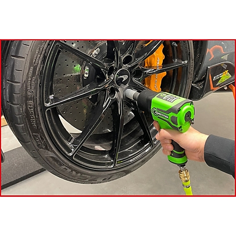 Hand nutzt einen grünen Druckluft-Schlagschrauber, um eine Radmutter an einem schwarzen McLaren-Sportwagenrad zu lösen.