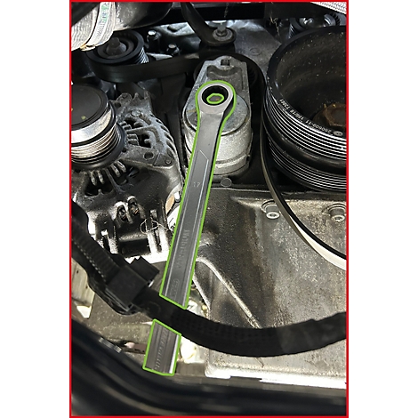 Ein Ringschlüssel setzt an einem Riemenspanner im Motorraum eines Autos an.