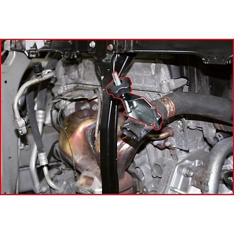 Ein Spezialwerkzeug zur Schlauchabklemmung, montiert an einem schwarzen Metallhalter im Motorraum.