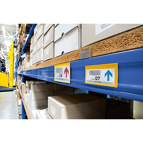 A warehouse shelf with boxes and labels. Barcodes and arrows can be seen on the labels. A forklift is visible in the background.