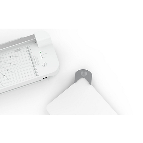 A white cutting machine with a transparent cutting area and green lights. A gray part is next to it.