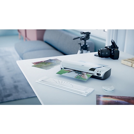 Close-up van een bureau met fotoprinter, camera en statief. Foto's worden afgedrukt. Heldere omgeving.