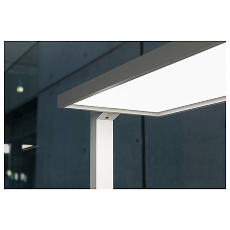 Gros plan d'une lampe de bureau LED blanche moderne avec un luminaire rectangulaire. L'arrière-plan est gris et flou.