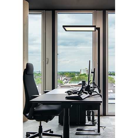 Bureau avec chaise de bureau et lampe devant une fenêtre donnant sur la ville.