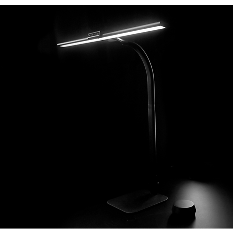 Lampe de bureau avec une lumière vive, éclairant une pièce sombre.