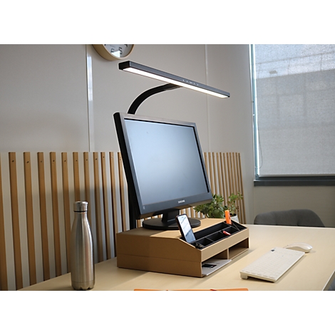 Moniteur sur un support en bois avec lampe de bureau LED intégrée et porte-stylo sur un bureau bien rangé.