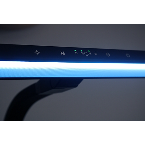 Gros plan sur le panneau de commande d'une lampe de bureau avec des voyants LED verts allumés et des icônes.