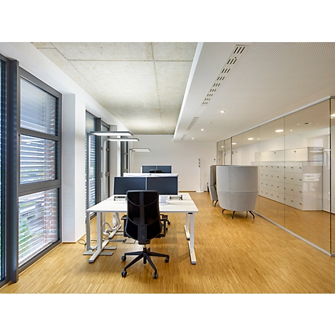 Espace de bureau lumineux avec des bureaux, des chaises et des façades vitrées. Plancher en bois, parois vitrées et éclairage moderne.