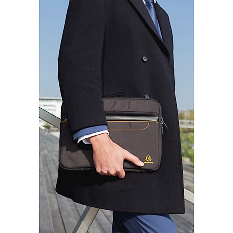 Eine Person in einem schwarzen Mantel hält eine braune Laptoptasche.