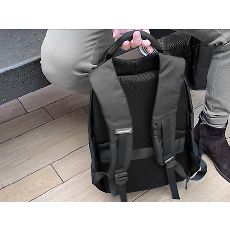 Ein Mann hält einen schwarzen Rucksack. Der Rücken ist mit gepolsterten Trägern und einem atmungsaktiven Rückenpolster versehen.