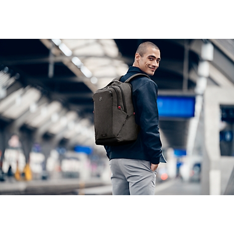 Ein Mann mit Rucksack an einem Bahnhof, schaut zurück.