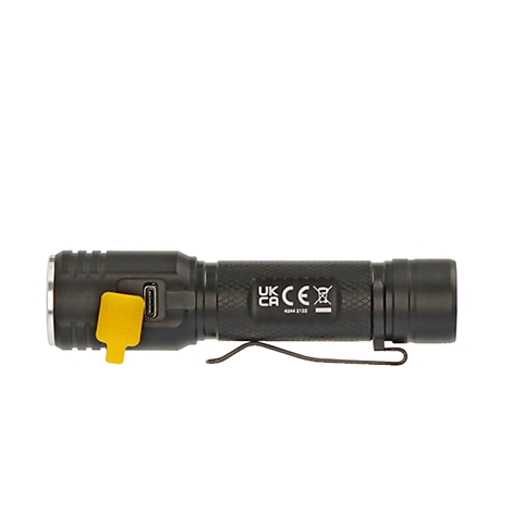 A man wearing a safety helmet climbs into a dark cave, exploring the rock. A flashlight illuminates the walls.