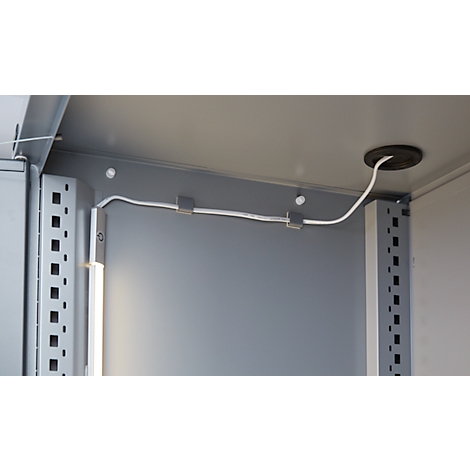 Interior view of a control cabinet with white cable running through an opening in the ceiling, secured with clips.