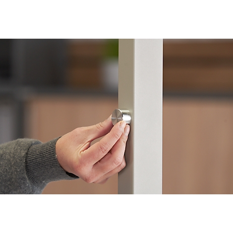 Close-up van een hand die een zilveren knop draait op een witte pilaar.