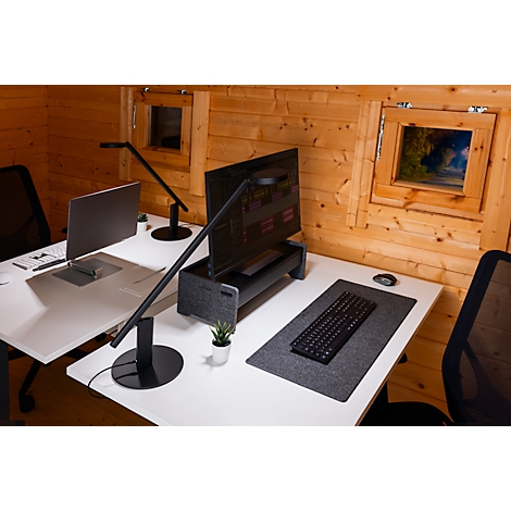 Two desks in a wooden house. Laptops, monitors and desk lamps are on the desks. Windows in the background.