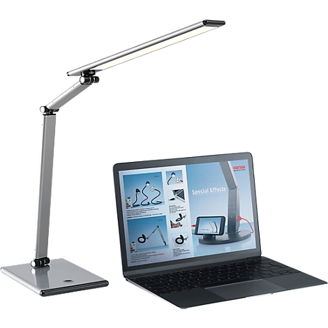 A silver desk lamp next to an open laptop. The screen shows examples of how the lamp can be used.