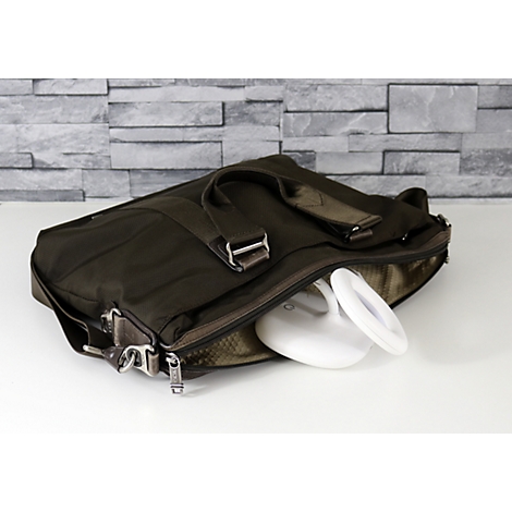 Braune Aktentasche, halb geöffnet. Eine weiße, moderne Schreibtischlampe liegt darin. Im Hintergrund eine graue Backsteinmauer.