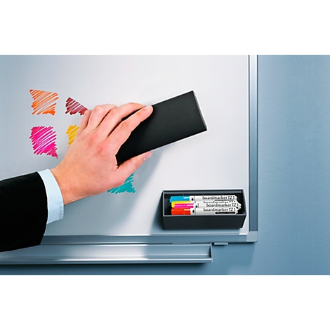 Hand wiping colorful markings from a whiteboard with a sponge, markers in a black box.