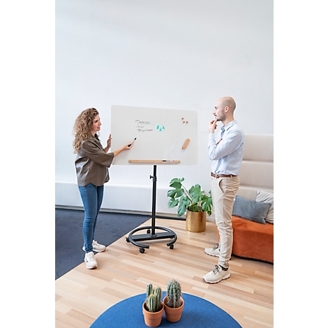 Une femme explique quelque chose sur un tableau blanc, un homme se tient à côté et réfléchit.