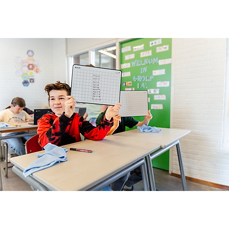 Ein Schüler hält im Unterricht eine beschriebene Whiteboard-Tafel hoch.