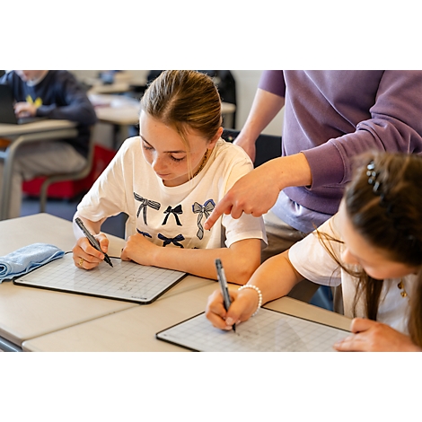 Schülerin schreibt konzentriert mit einem Stift auf ein weißes Whiteboard-Tablet im Unterricht.