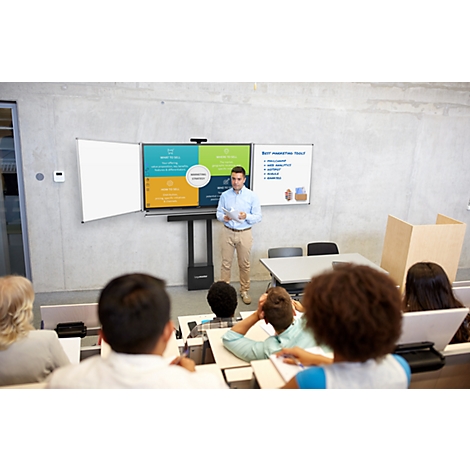 Ein Mann präsentiert vor Studenten; im Hintergrund eine Präsentation auf verschiedenen Bildschirmen.