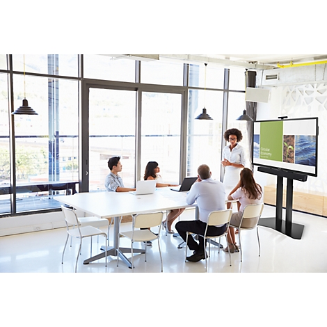 Un groupe de collègues dans une salle de conférence lumineuse suivant une présentation sur grand écran.