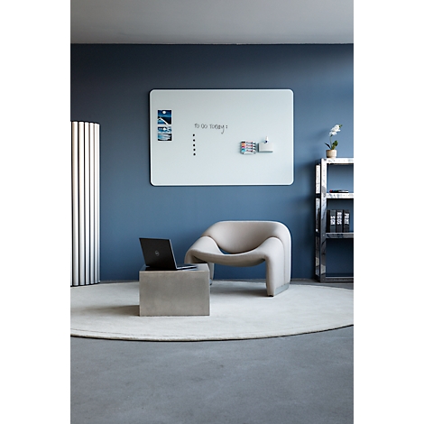 Un bureau moderne avec des meubles et des accessoires design. Un tableau mémo, une chaise, une table basse et un ordinateur portable sont visibles.
