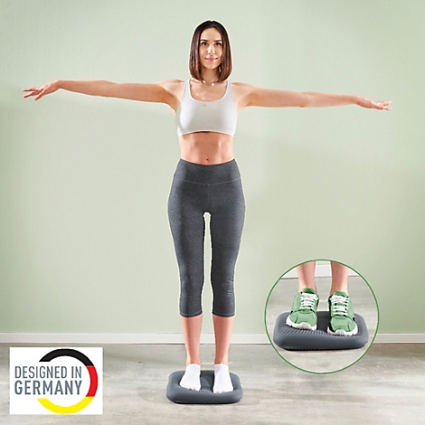 Eine Frau steht mit ausgestreckten Armen auf einem Balance-Pad. Sie trägt Sportkleidung. Im Hintergrund ist ein Balance-Pad im Detail abgebildet.