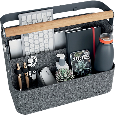 Een vrouw met kort haar plaatst een grijze vilten organizer met houten handvat in een lichtblauw reksysteem.