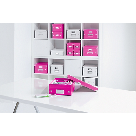 An open, pink storage box on a white table with other boxes in a white shelf.