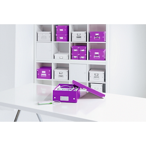 Open purple box with cables on a white table, shelves with boxes in the background.