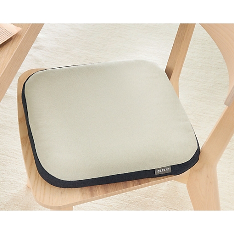 Een vierkant beige zitkussen met een donkerblauwe rand op een houten stoel. Certificeringen en onderscheidingen.