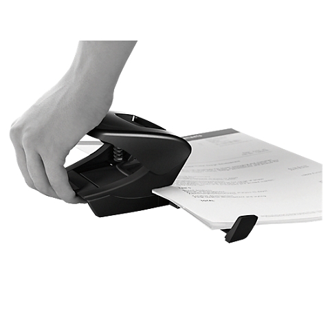 A hand operates a black hole punch to punch holes in paper.