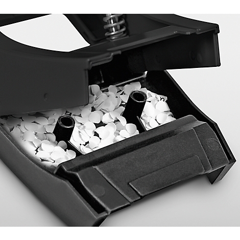 Close-up of a hole puncher filled with white paper confetti. Black plastic, detail shot.