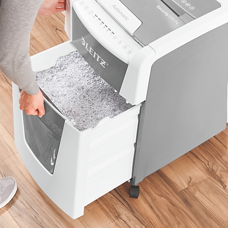 Person emptying a paper shredder. The waste container is filled with shredded paper. Leitz logo clearly visible.