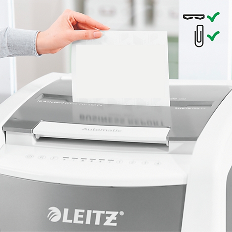Hand legt Papier in Aktenvernichter. Neben dem Gerät Symbole für Büroklammern und Heftklammern mit Häkchen.