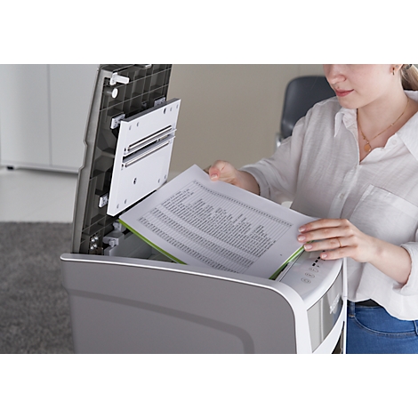 A woman is placing a document into a scanner. The scanner lid is open.