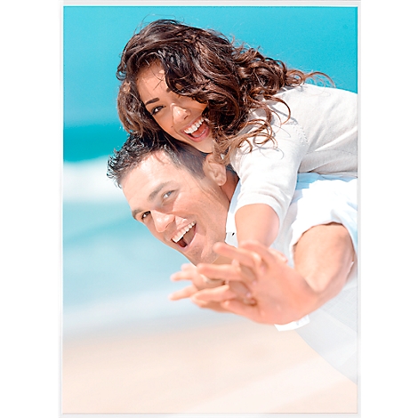 Happy couple at the beach: Man carries laughing woman on his shoulders.