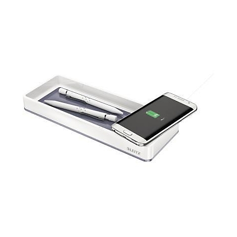 Witte pennen in een bakje naast een smartphone op een oplaadstation. De smartphone laadt op.