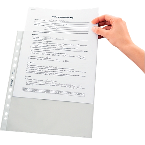 Hand holds a sheet of paper out of a transparent foil folder with a rental agreement on it.