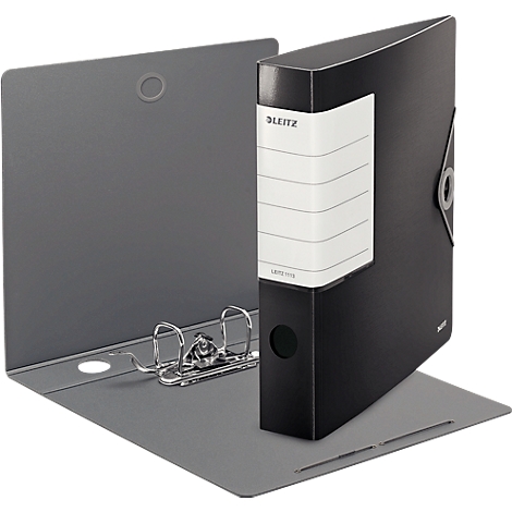 A black Leitz binder stands open. The gray inside can be seen, with ring mechanism. A white label with lettering is attached.